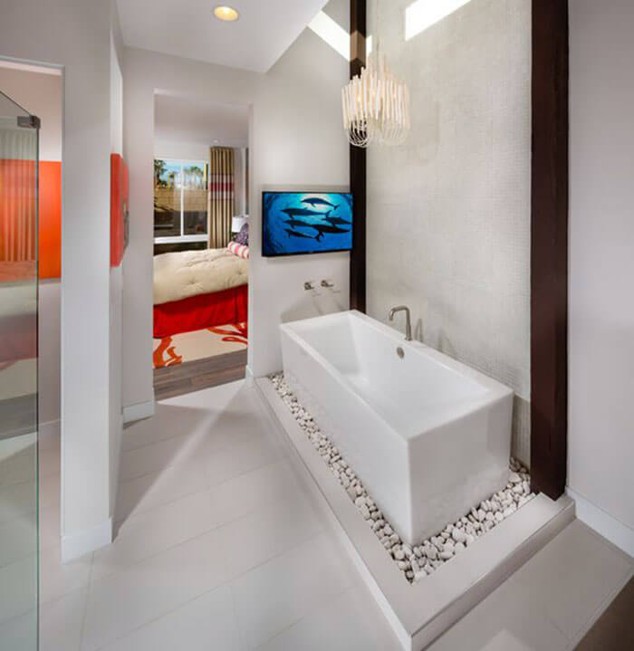 Minimalist modern master bathroom with elevated tub on white rocks