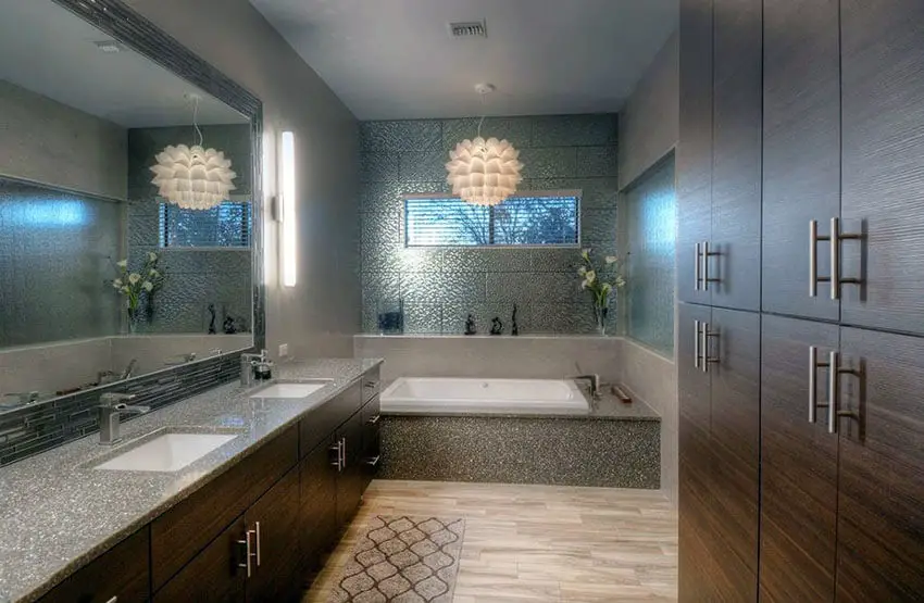Modern bathroom with brown vanities and pendant chandelier over bathtub