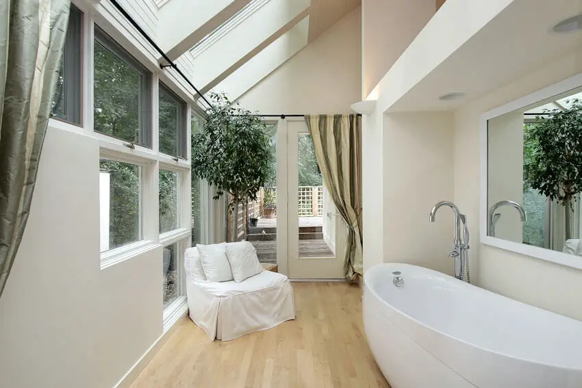 Modern bathroom with wood floors large windows and lounge chair